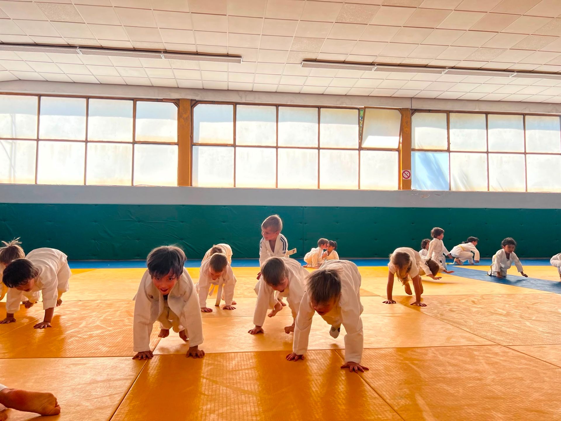 Aula de judo com crianças em judogi branco no tatami