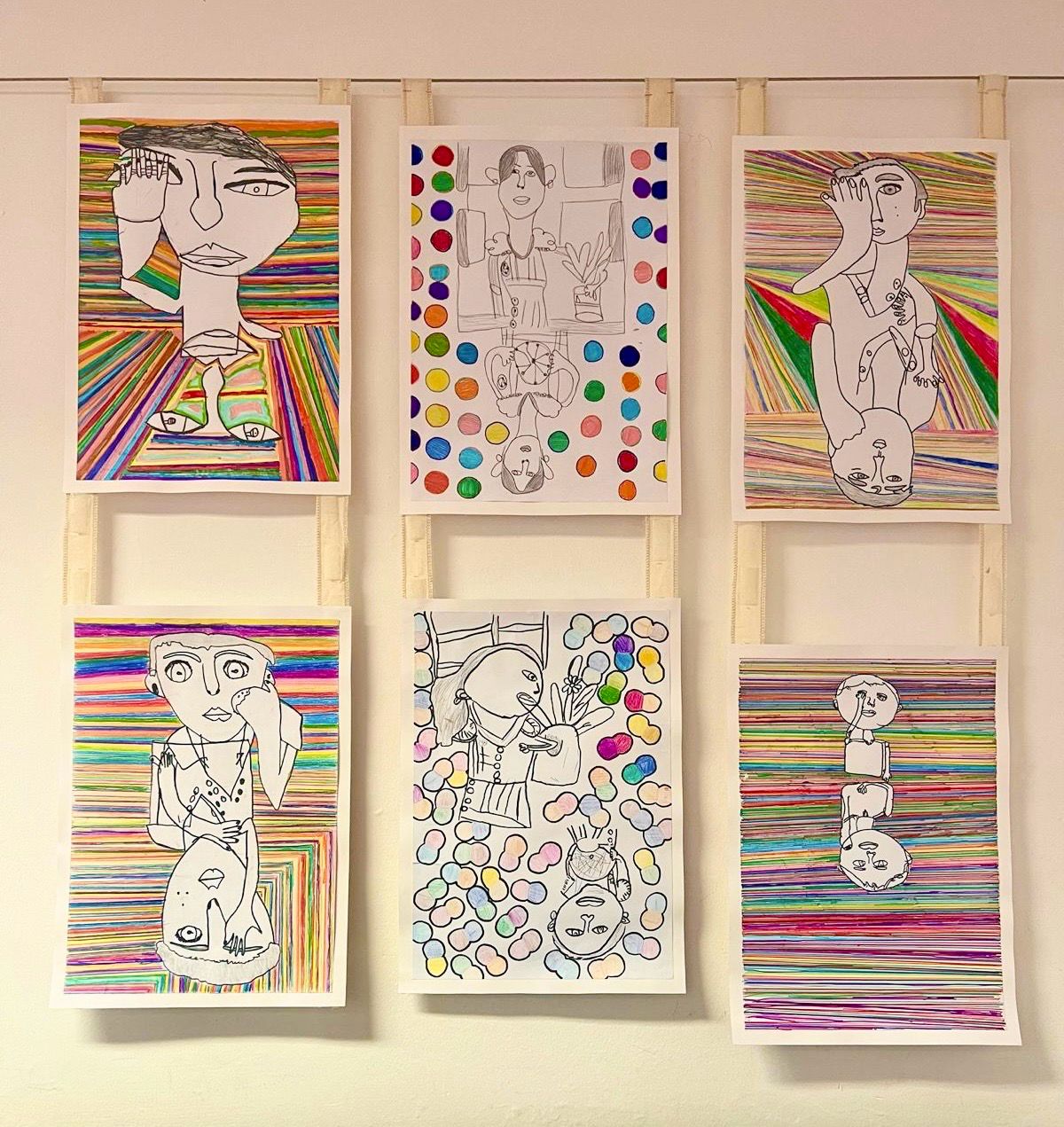 Colourful portrait drawings made by the pupils displayed on a wall