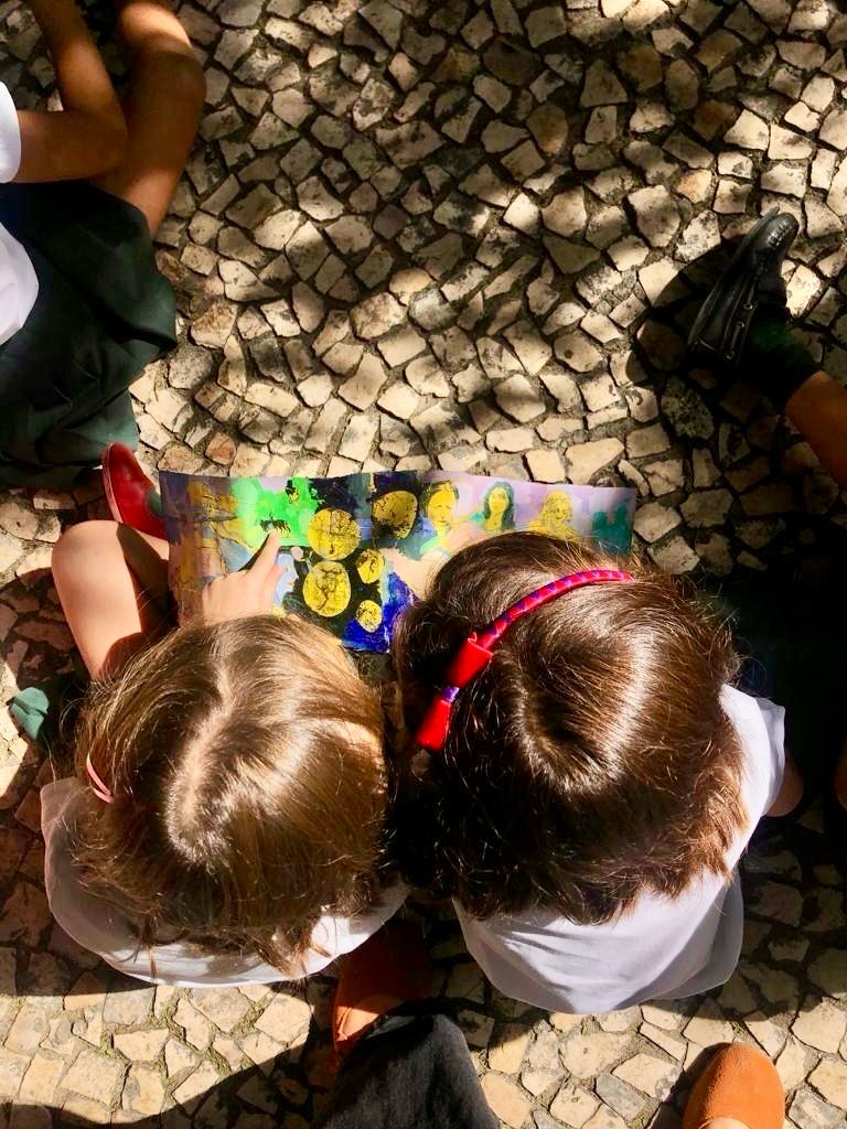 Two children observing a painting in the courtyard with Portuguese pavement